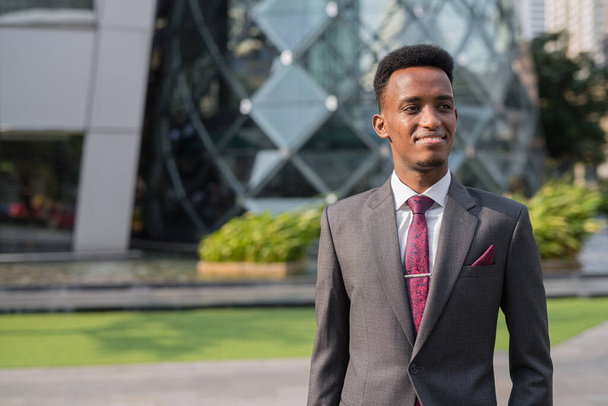 Portrait of young successful African businessman outdoors in city - Foto, afbeelding