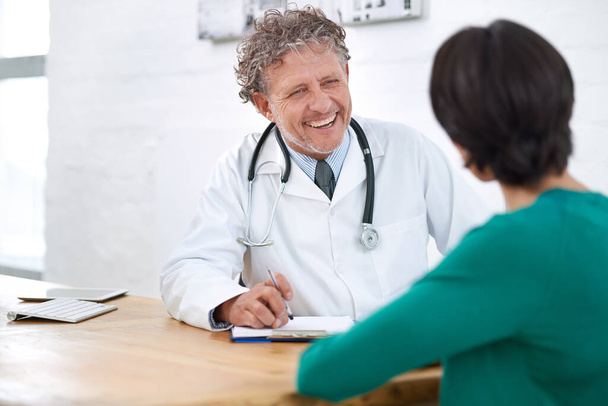 Hes got a wonderful bedside manner. Shot of a smiling mature doctor having a consultation with a patient. - Foto, afbeelding