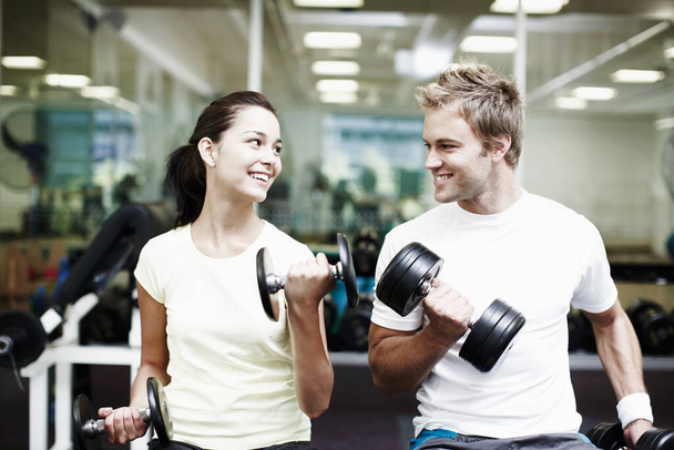 Поехали. Снимок двух человек, тренирующихся с гантелями в спортзале. - Фото, изображение