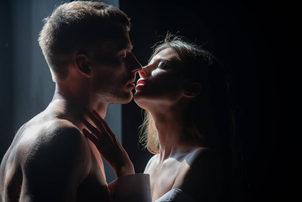 Passionate kiss. Man embracing and going to kiss sensual woman. Loving couple kissing over black background. Real love on Valentines Day. - Valokuva, kuva