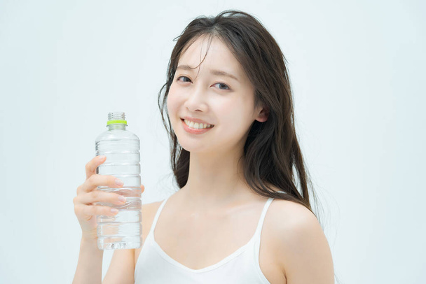 Woman drinking water from a plastic bottle indoors - Photo, Image