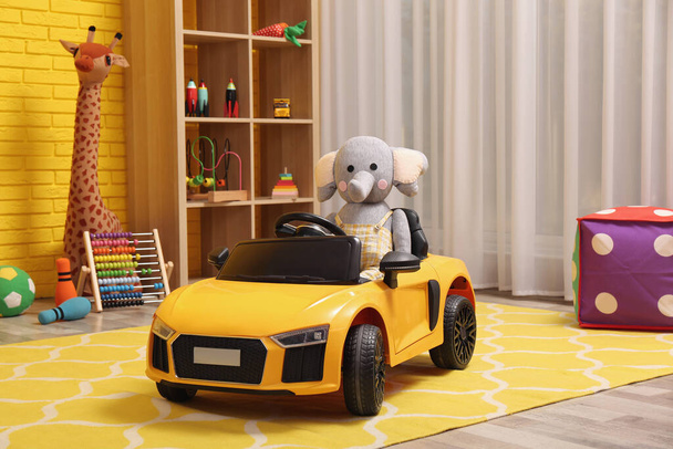 Child's electric car with toy elephant in playroom - Foto, afbeelding
