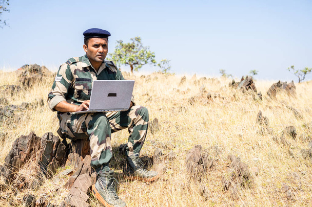 Servicemann mit Laptop auf dem Gipfel des Berges zum Sammeln von Daten - Konzept der Intelligenz, Internetverbindung, Kommunikation und Überwachung - Foto, Bild