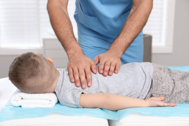 Orthopedist massaging child's back in clinic, closeup. Scoliosis treatment - Foto, Imagen