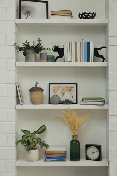 Cat shaped bookends with books and different decor on shelves indoors. Interior design - Foto, afbeelding