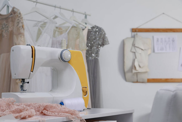 Sewing machine and fabric on table in dressmaking workshop - Фото, зображення