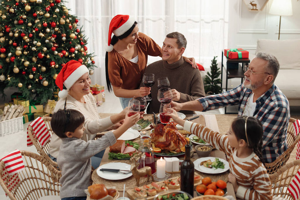 Happy family clinking glasses of drinks at festive dinner indoors. Christmas celebration - Foto, imagen