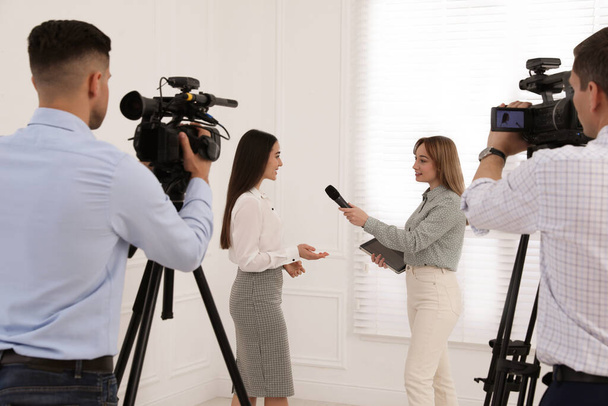 Professional journalist interviewing young business woman and cameramen shooting video for broadcast - Fotografie, Obrázek