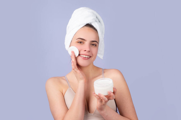 Cosmetic products. Woman with a facial mask. Charming pretty model after bath wrapped in towel applying using face mask, sensual face. Head shot beautiful woman applying moisturizer on skin. - Fotó, kép