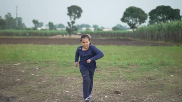 Langzame opname van een Indiase jongen op het landbouwgebied van India. Suikerrietteelt op de achtergrond. Indiase jongen op de vlucht voor fysieke fitness. - Video