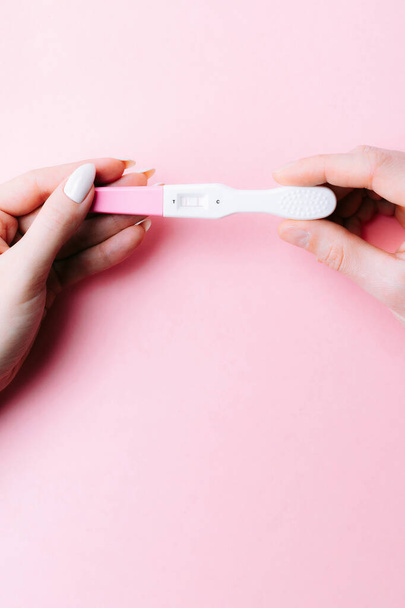 Pregnancy test couple. Positive woman pregnant test in hands with pink silk ribbon on pink background. New life and new family. Motherhood, pregnancy, birth control concept - Foto, imagen