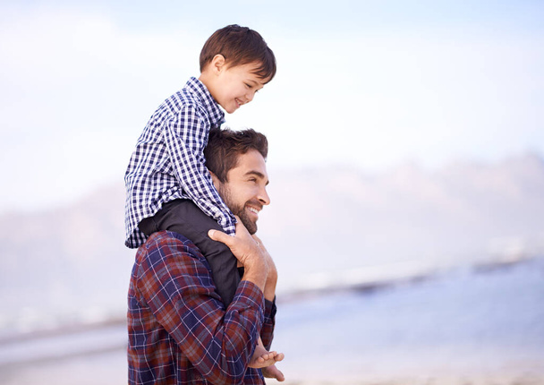 Où allons-nous ensuite papa. Un père portant son jeune fils sur ses épaules avec un sourire. - Photo, image