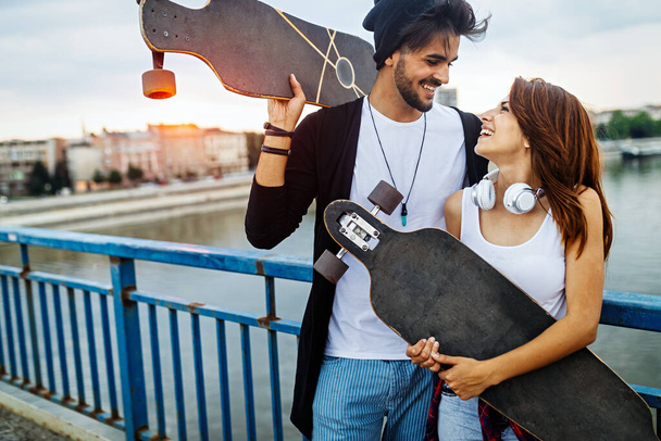 Picture of young attractive couple carrying skateboards and having fun - Valokuva, kuva