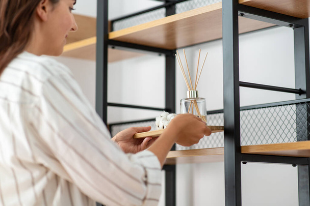 woman placing aroma reed diffuser to shelf home - Fotoğraf, Görsel