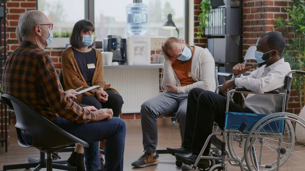 Hombre con discapacidad que asiste a una sesión de terapia aa reunión con personas durante la pandemia covid 19 - Foto, Imagen