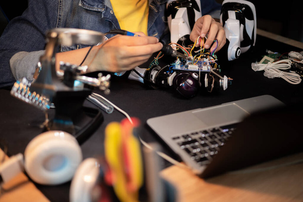 Стол с ноутбуком, инструментами, паяльным оборудованием. Мальчик чинит робота, припои кабели, играет с электроникой, строит игрушки. - Фото, изображение