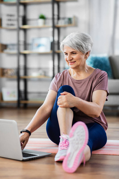 happy woman with laptop exercising at home - Photo, image