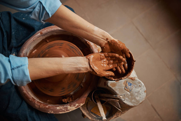 Craft woman working in pottery workshop while making ceramic tableware - Foto, afbeelding