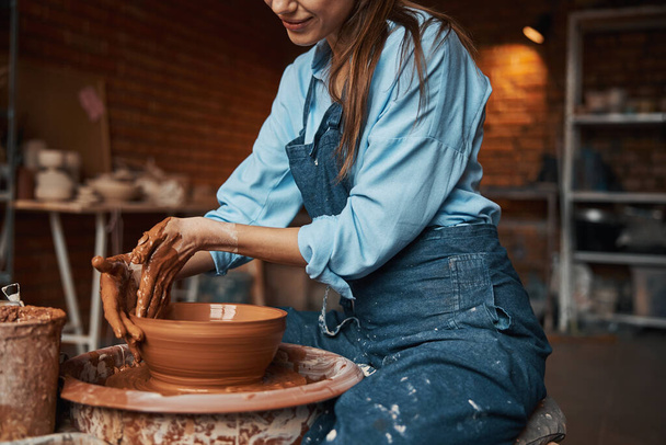 Beautiful young lady shaping clay bowl in pottery workshop - Φωτογραφία, εικόνα