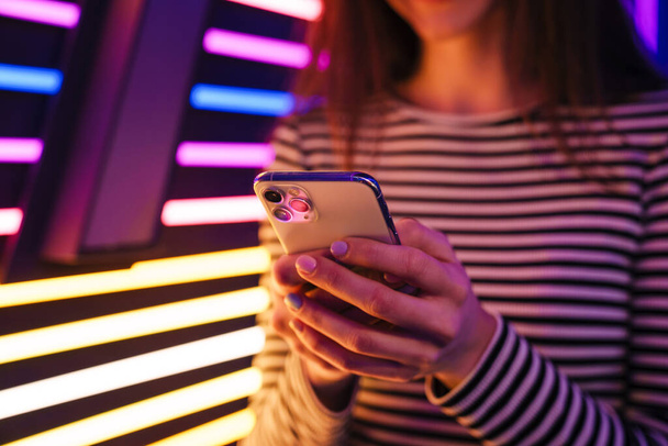 Young brunette woman in striped long sleeve using mobile phone indoors - Foto, immagini