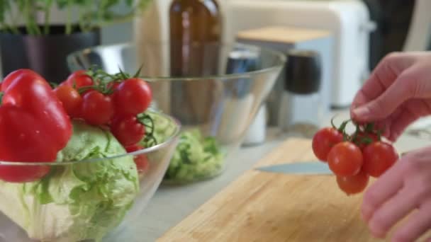 女性はキッチンで野菜サラダのための新鮮な赤チェリートマトを取る - 映像、動画