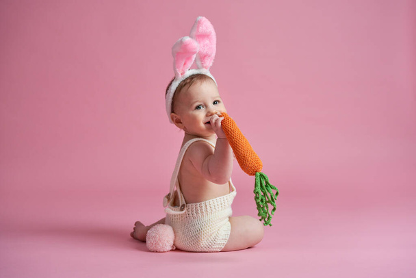 Маленька дитина в костюмі кролика, що їсть моркву
  - Фото, зображення