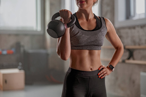Confident fit γυναίκα κρατώντας kettlebell στο γυμναστήριο - Φωτογραφία, εικόνα