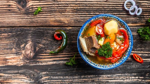 Shurpa leves tányéron keleti dísz, fa háttér. Első látásra. hagyományos ázsiai, üzbég, közel-keleti leves marhahússal vagy báránnyal és zöldségekkel. Shorpa, sherpa, chorba, élelmiszer-recept háttér. - Fotó, kép