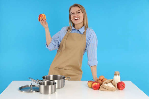 Concept of cooking with young woman on blue background - Zdjęcie, obraz