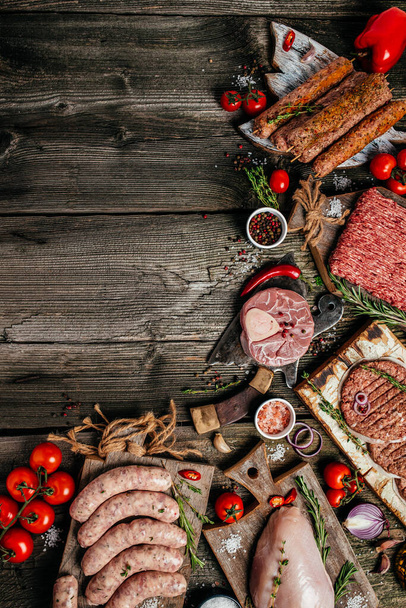 Különböző típusú grill és bbq nyers húsok. Csirke, steak, kolbász, darált marhahús kebab, sertés gyógynövényekkel, fűszerek fa háttéren. függőleges kép. Kiváló kilátás. a szöveg helye. - Fotó, kép