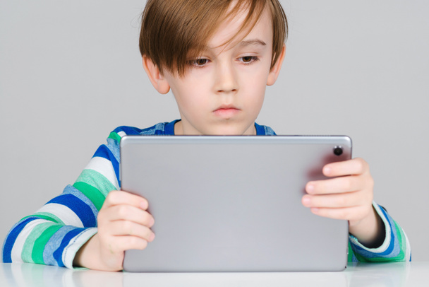 Smart boy with tablet for online lesson. Cute serious kid using digital tablet. Online school, modern technology. Schoolboy learning at home. Children, technology and education concept. - Photo, Image