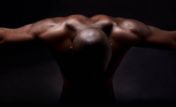 Czyste mięśnie i męskość. Studyjne ujęcie muskularnego Afrykanina pochylającego się do przodu. - Zdjęcie, obraz