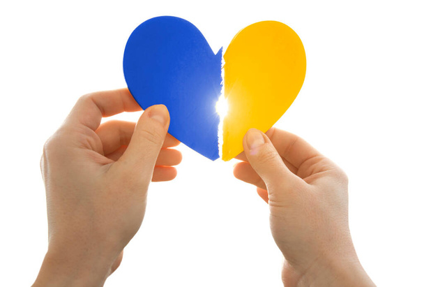 The broken wooden heart in colors of Ukrainian flag in woman's hands - Foto, Imagem