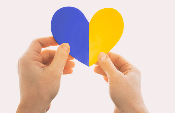 The wooden heart in colors of Ukrainian flag in woman's hands - Foto, imagen
