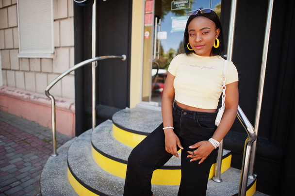 Beautiful fashionable young african american woman posing in street stairs, sunglasses, yellow top. Fashion summer photo. Bright colors. Nice view afro people. - Valokuva, kuva