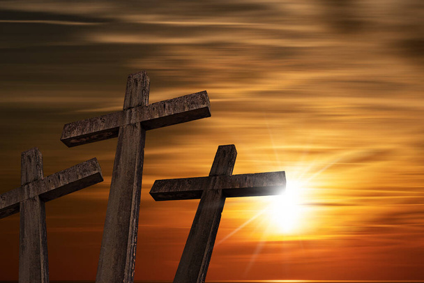 Tres cruces religiosas de piedra contra una hermosa puesta de sol con rayos de sol y espacio de copia. Símbolo religioso del Viernes Santo. - Foto, Imagen