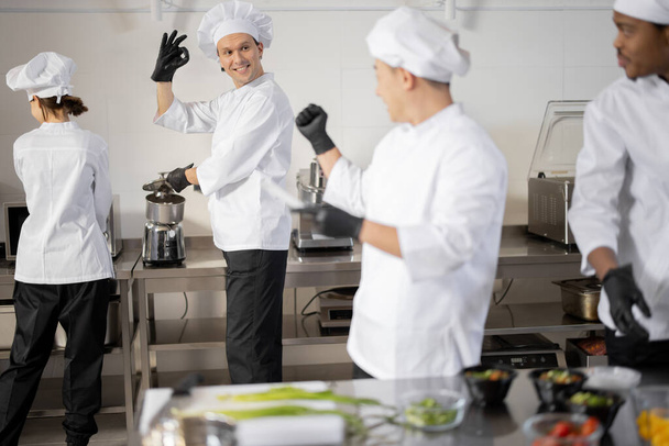 Cocineros felices cocinando en cocina profesional - Foto, Imagen