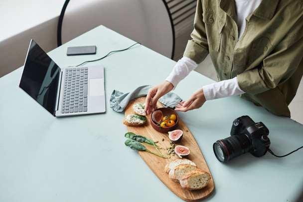 Υψηλής γωνίας άποψη στο θηλυκό φωτογράφος τροφίμων τακτοποίηση γκουρμέ πιάτο με στηρίγματα, ενώ εργάζονται σε στούντιο, αντιγραφή χώρου - Φωτογραφία, εικόνα