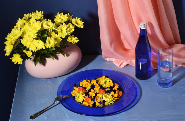 Arrangement of plate with flowers, glass of water and vase with beautiful yellow flowers - Foto, Bild