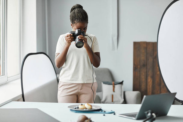 Retrato mínimo de una joven afroamericana tomando fotografías de comida en estudio, espacio para copiar - Foto, Imagen