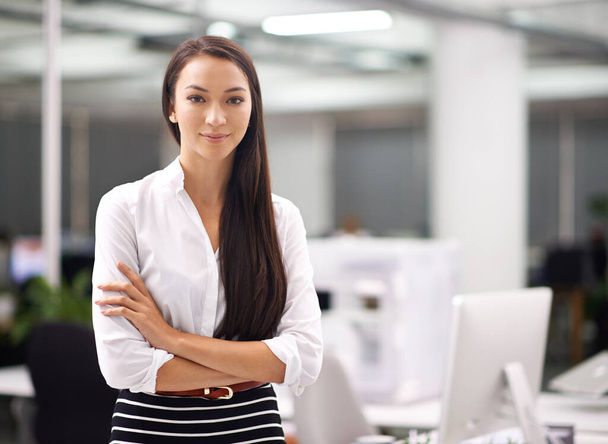 Уверенность в бизнесе. Портрет привлекательной молодой бизнесвумен, стоящей со сложенными в офисе руками. - Фото, изображение