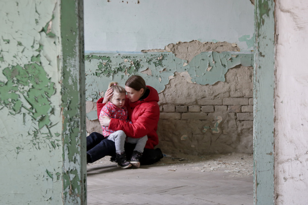 Madre e sua figlia nell'edificio distrutto. Guerra, rifugiati, concetto di crisi di guerra. - Foto, immagini