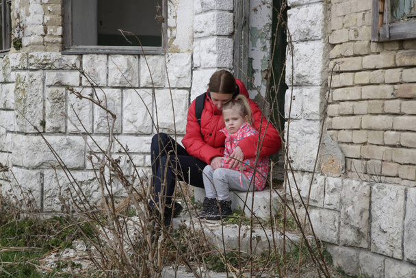 Η μητέρα και η κόρη της στο κατεστραμμένο κτίριο. Πόλεμος, πρόσφυγες, πολεμική κρίση. - Φωτογραφία, εικόνα