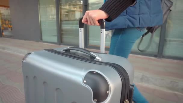 Nahaufnahme einer Frau, die das Hotel mit Gepäck verlässt. Sie rollt Koffer die Straße hinunter - Filmmaterial, Video