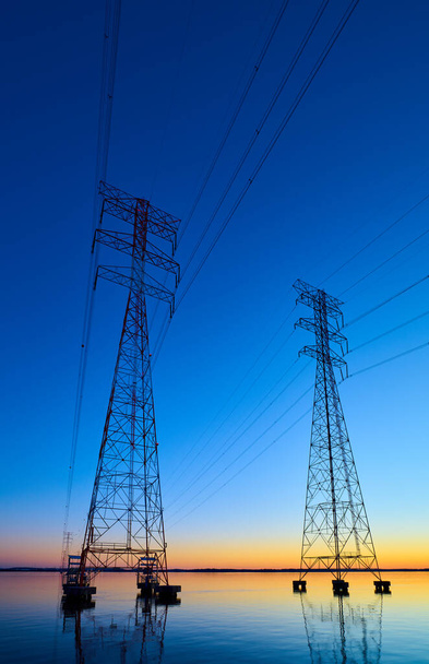Lignes de transport à haute tension traversant Wheeler Lake au crépuscule près d'Athènes AL. Pylônes électriques au coucher du soleil. Puissance et énergie. - Photo, image