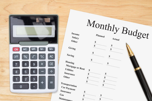 Haciendo tu presupuesto mensual con una calculadora y un bolígrafo en un escritorio de madera  - Foto, imagen