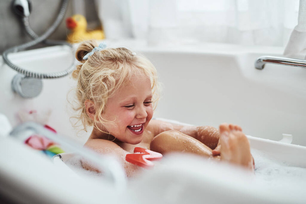 Bath time is my favourite time. Cropped shot of an adorable little girl taking a bubble bath during her morning routine at home. - Zdjęcie, obraz