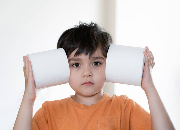 Portrét mladý chlapec s vyhlídkou ven a hrát si s toaletním papírem, Kid uvedení WC role na hlavě, Dítě drží dvě bílé tkáně, Dětská zdravotní péče koncept - Fotografie, Obrázek