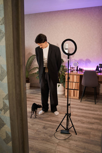 Uomo vestito elegante in piedi di fronte alla lampada e preparare le riprese del suo video blog - Foto, immagini