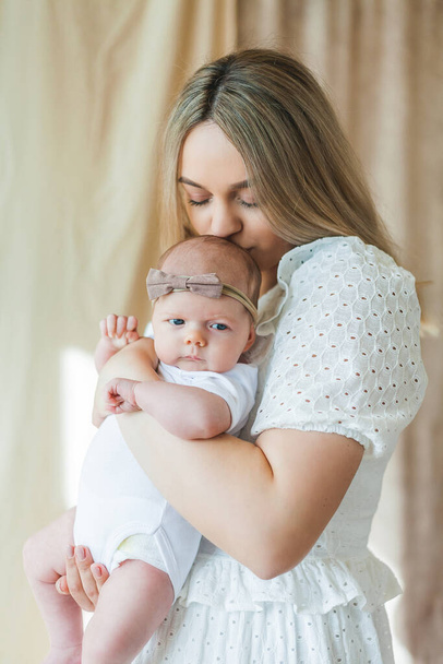 A fiatal, gyönyörű, kék szemű anya karjaiban tartja újszülött kislányát. Anyaság. Vigyázz magadra. Kicsim!. - Fotó, kép